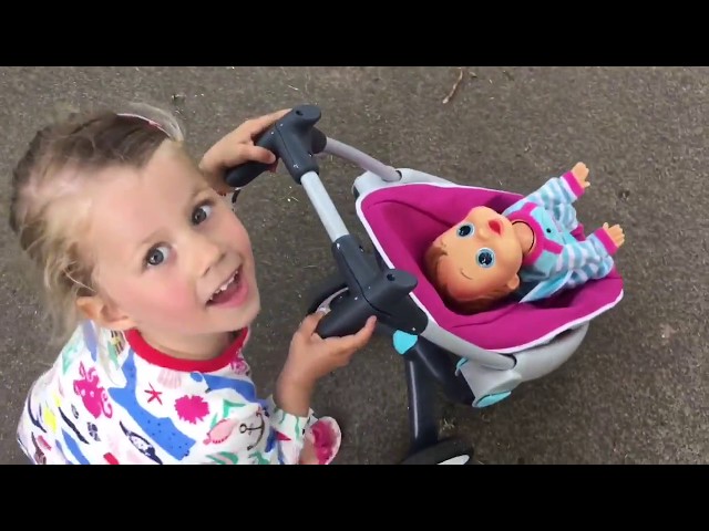 Little girl pushing stroller at park  / Baby Wow Charlie Doll
